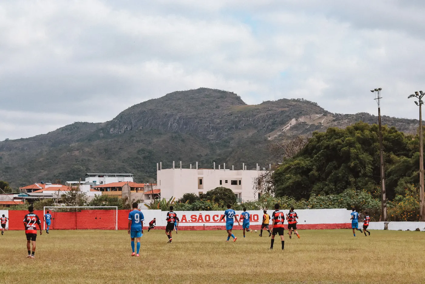 Partido de fútbol en la cancha de la Associação Atlética São Caetano, con un cerro de fondo